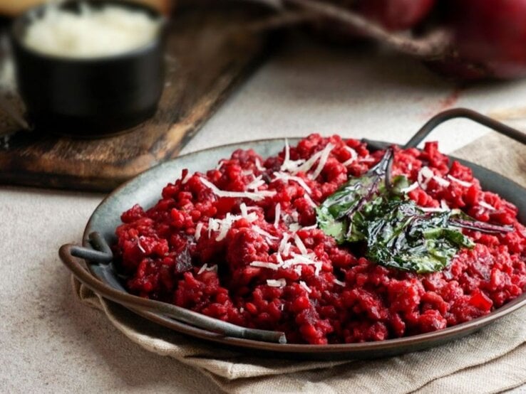 Teller mit vegetarischer One Pot Pasta in Tomaten- und Rote-Bete-Sauce, garniert mit Spinat und Käse.