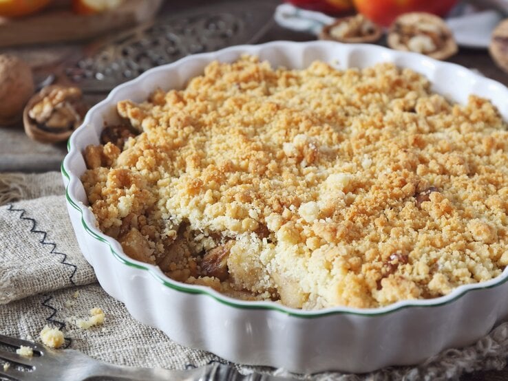Apfelkuchen mit Streusel und Walnüssen in runder Form / Apfelschnitten, frisch Walnüsse, Gabel